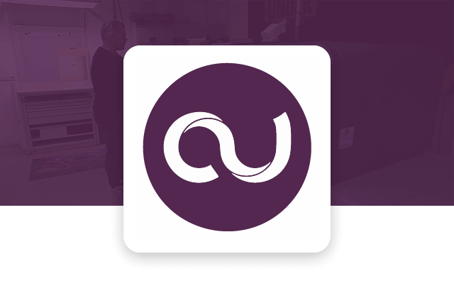 Cards Unlimited logo - Man operating a Ricoh printer in a dimly lit room. The scene is overlaid with a purple tint, and a white logo featuring a stylized "AU" is on the right.