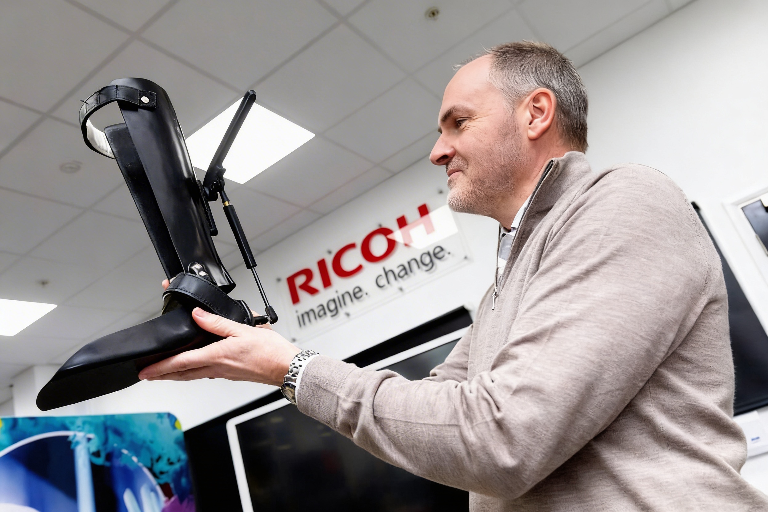 Engineer holding an advanced robotic prosthetic leg in a technology lab.