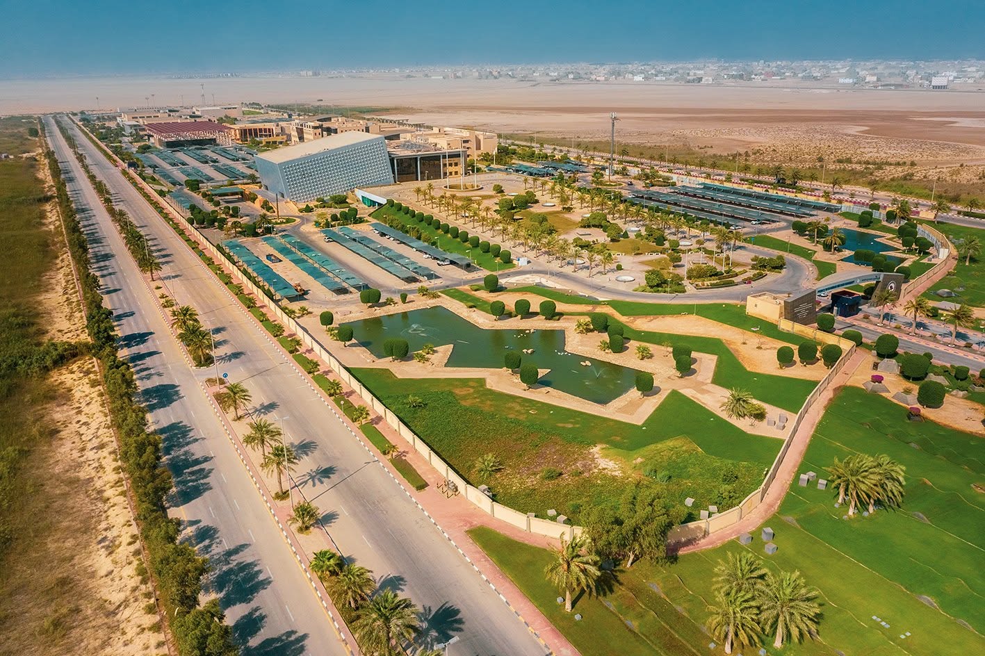 Aerial view of a modern business complex with landscaped gardens and palm-lined roads