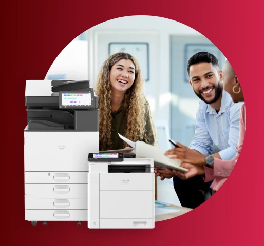 Office printers displayed in front of a group collaborating at a desk in a modern workspace.