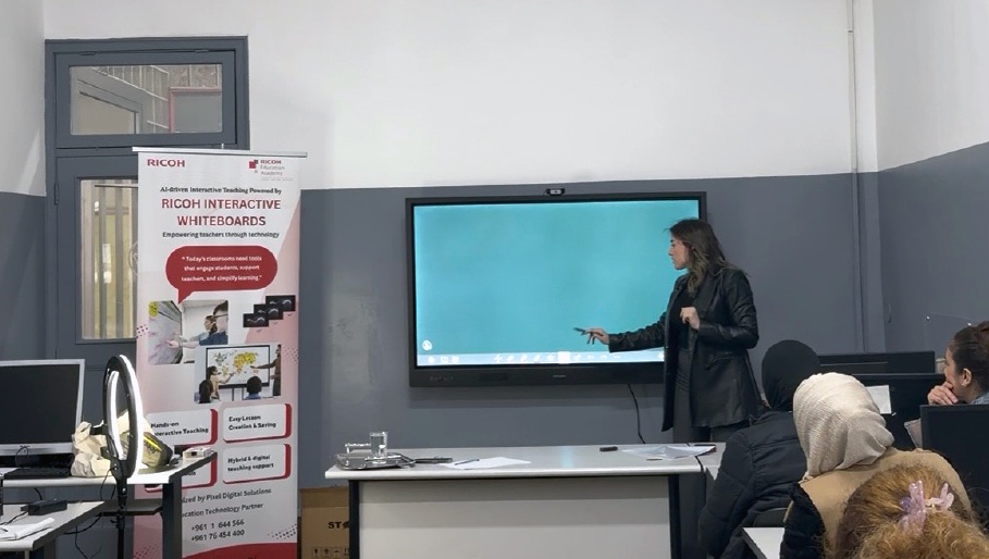 Interactive classroom training session with a presenter using a Ricoh interactive whiteboard while participants observe and engage in a modern digital learning environment.