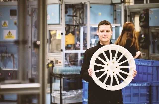 An employee holding a 3D-printed polypropylene wheel hub.