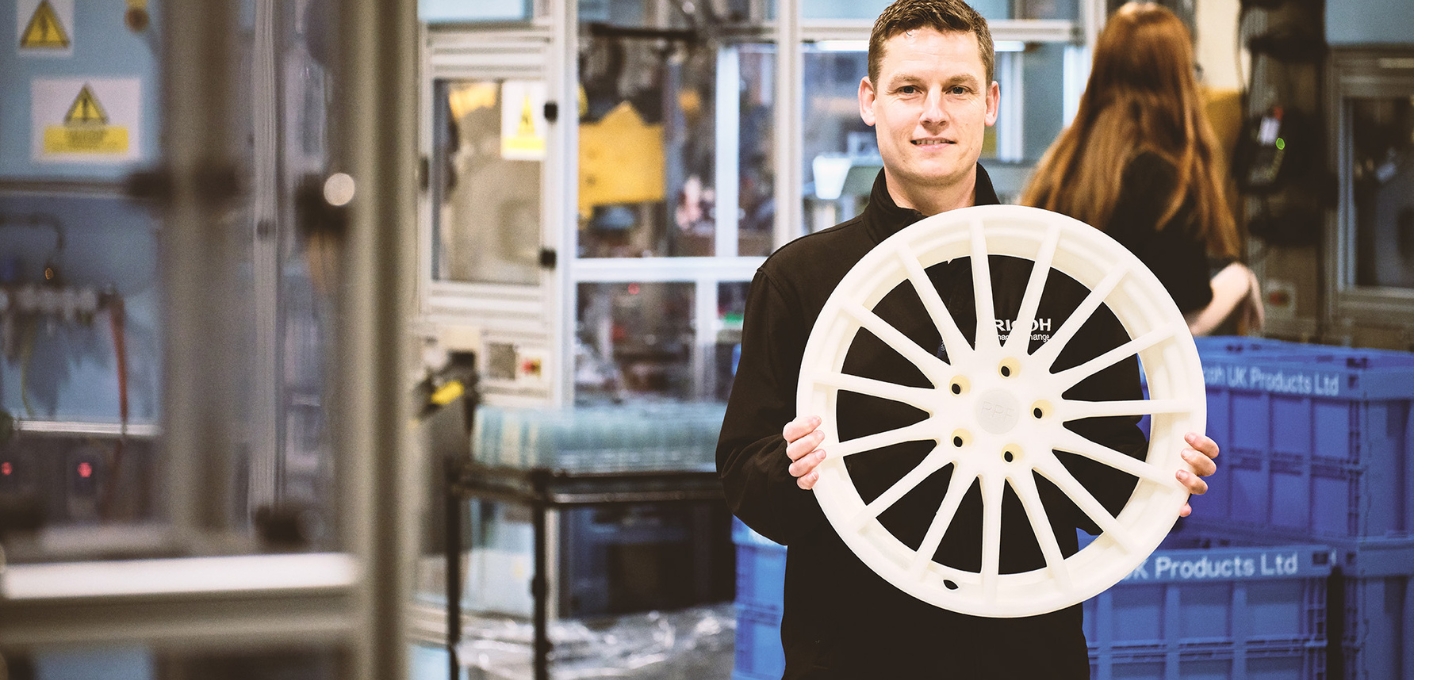 Ricoh 3D Senior Engineer, Richard Minifie, holding a 3D-printed automotive prototype.