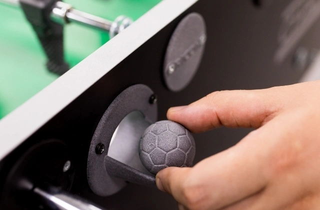 A 3D-printed football being placed onto a football table.